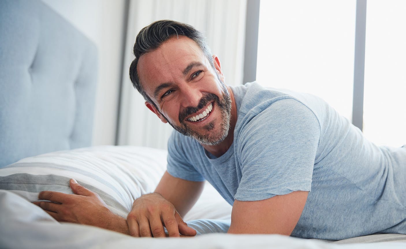 smiling man laying in a bed