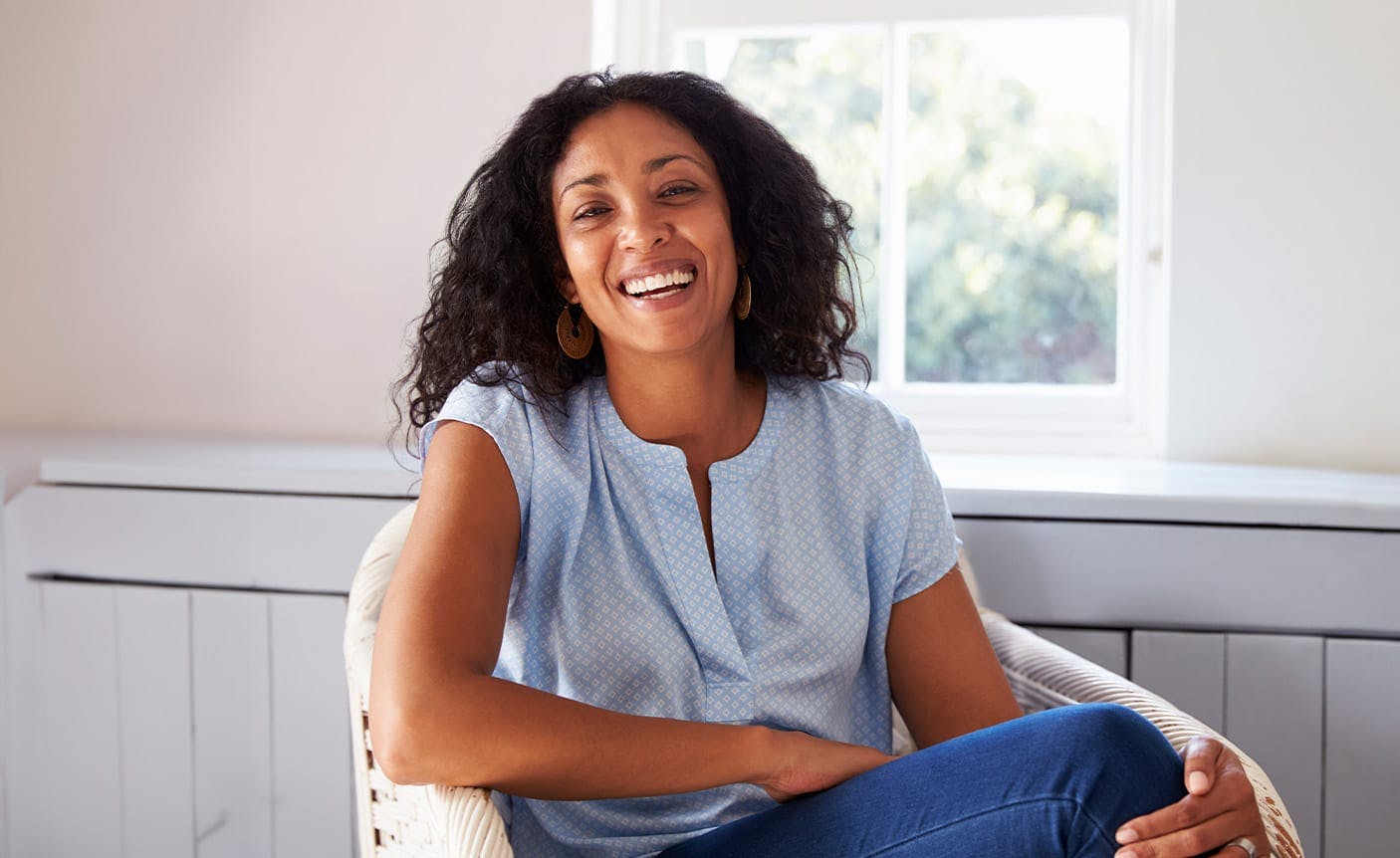 woman smiling, sitting in a chair