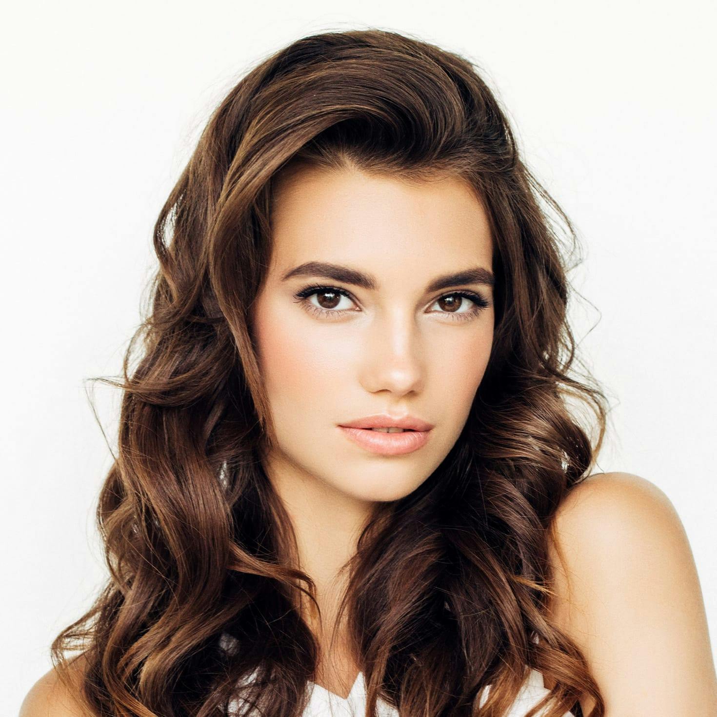 woman smiling, holding a straw hat in front of her