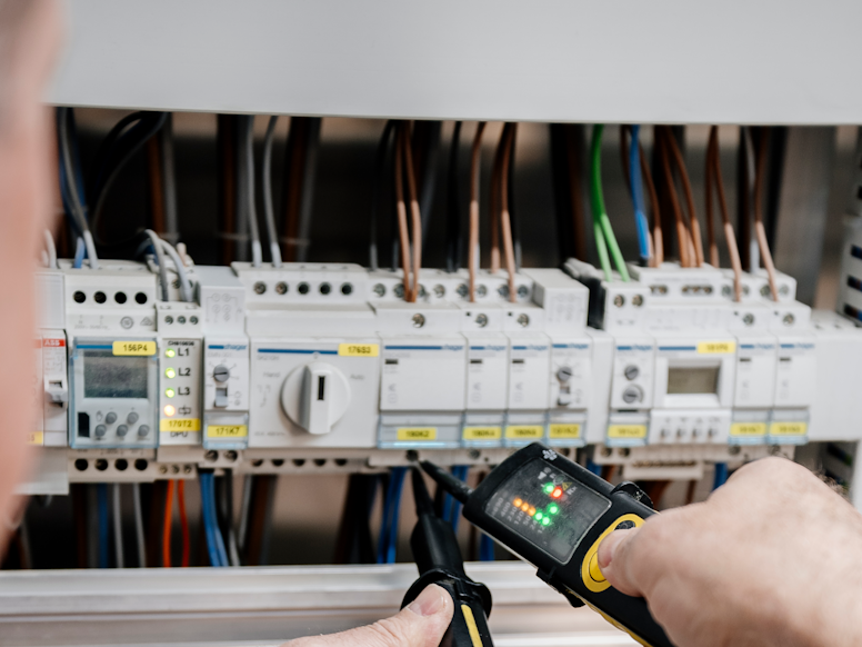 Elektroinstallateur arbeitet an einem Schaltschrank.