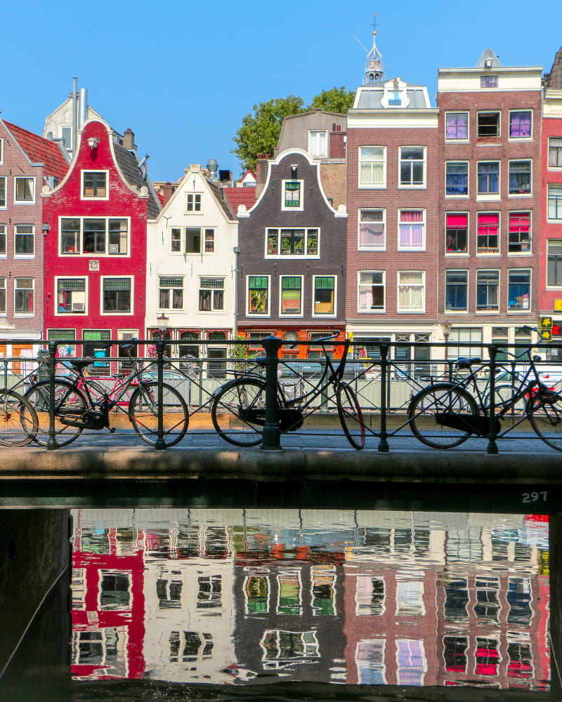 Image of bikes against a railing on a canal in Amsterdam