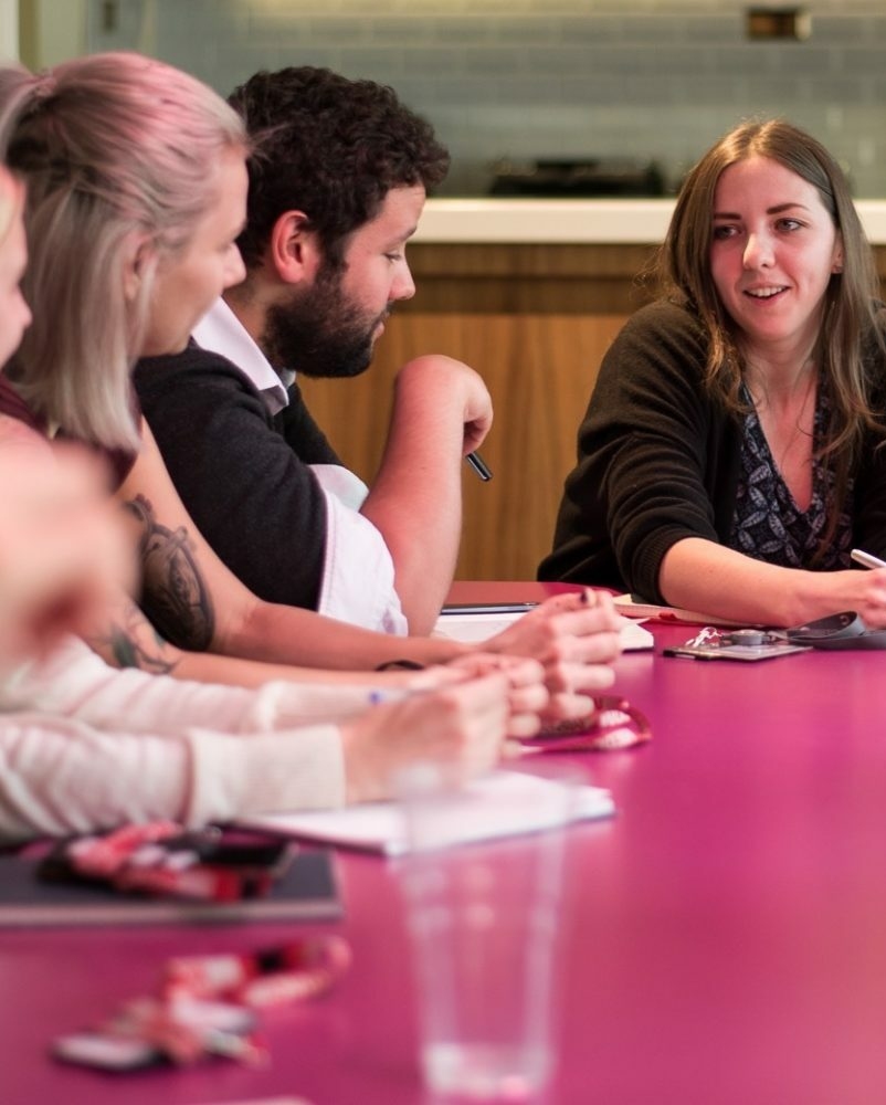 Image of people at a table talking to one another