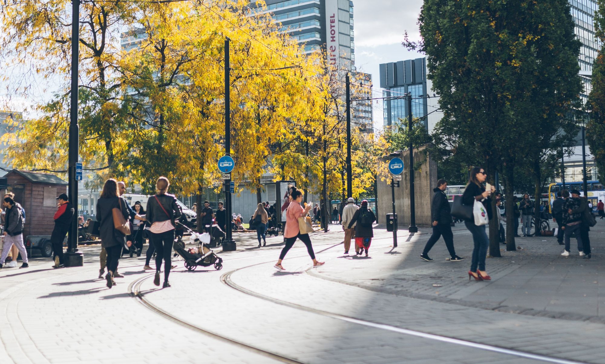 Image of people walking across a Manchester street and tram tracks