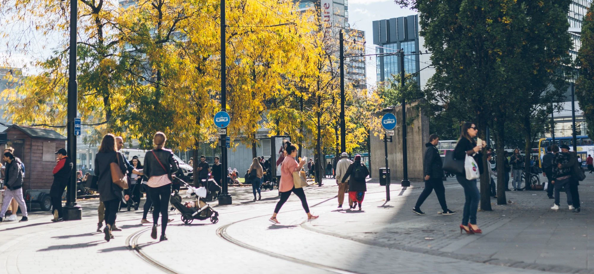 Image of people walking across a Manchester street and tram tracks