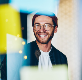 EssenceMediacom employee with hat and glasses smiling at camera