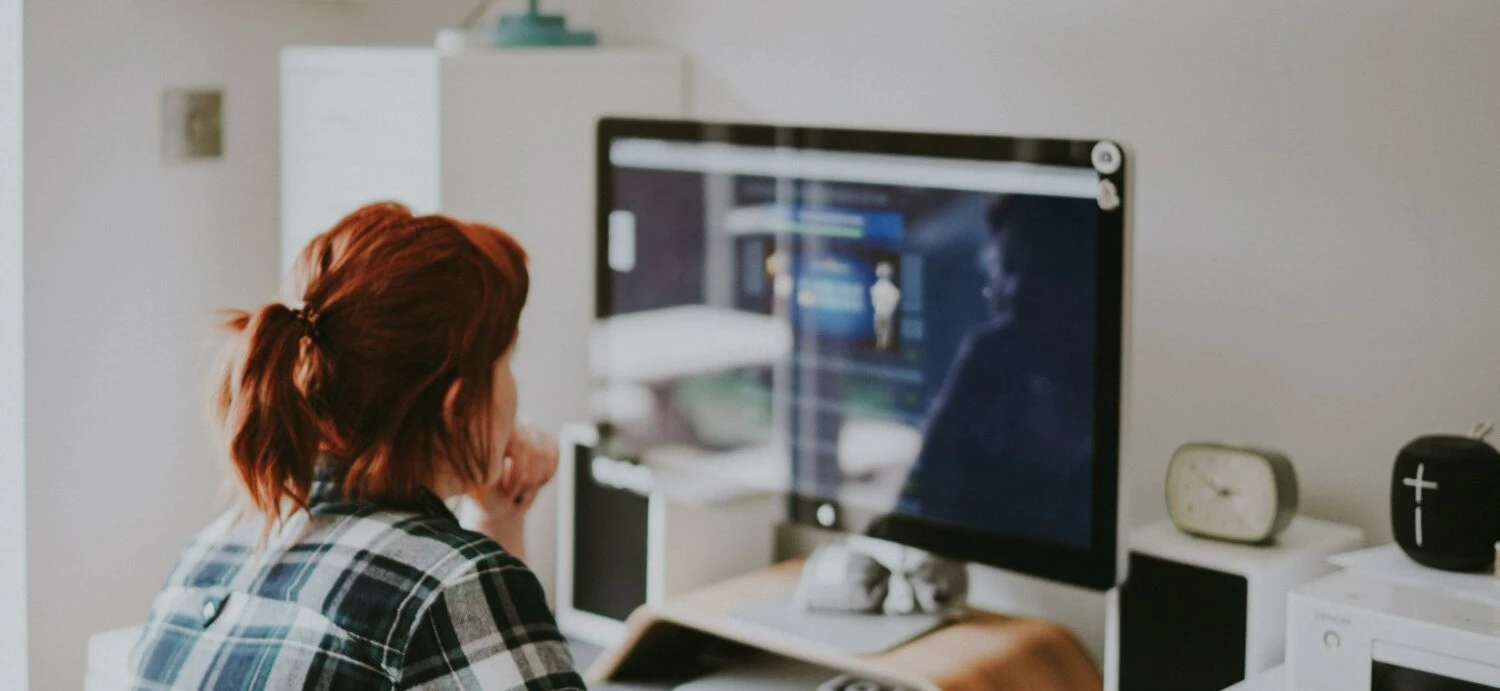 A woman sits at a computer considering her investment portfolio
