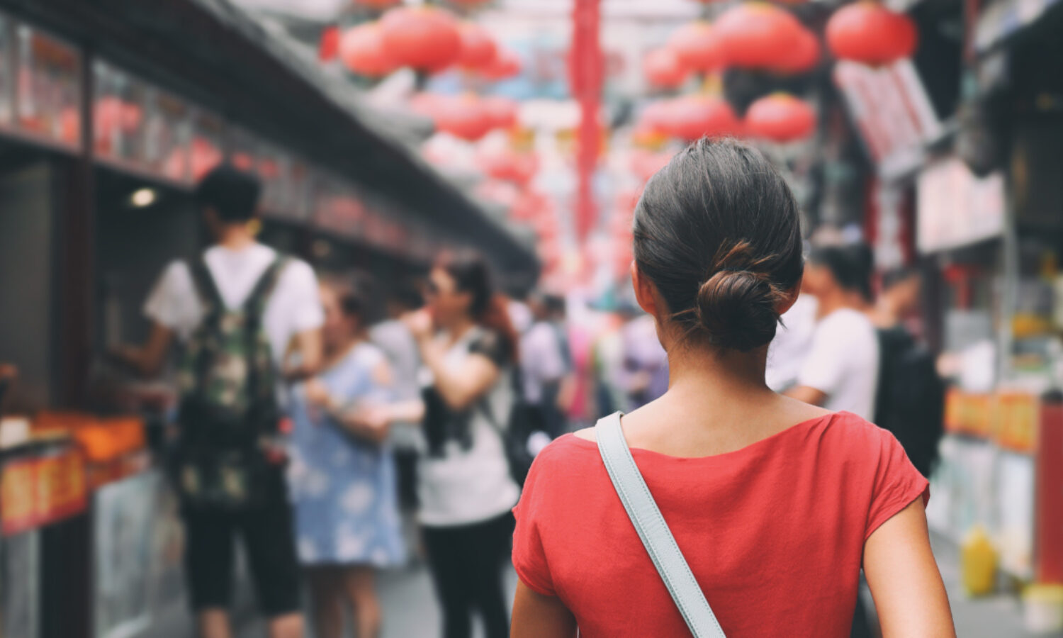 Seen from behind, a woman walks down a street in China.