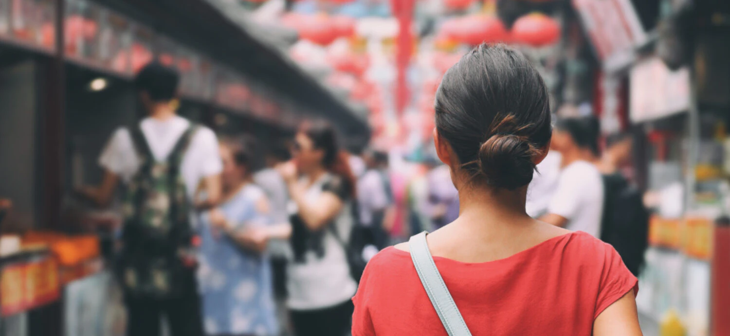 Seen from behind, a woman walks down a street in China.