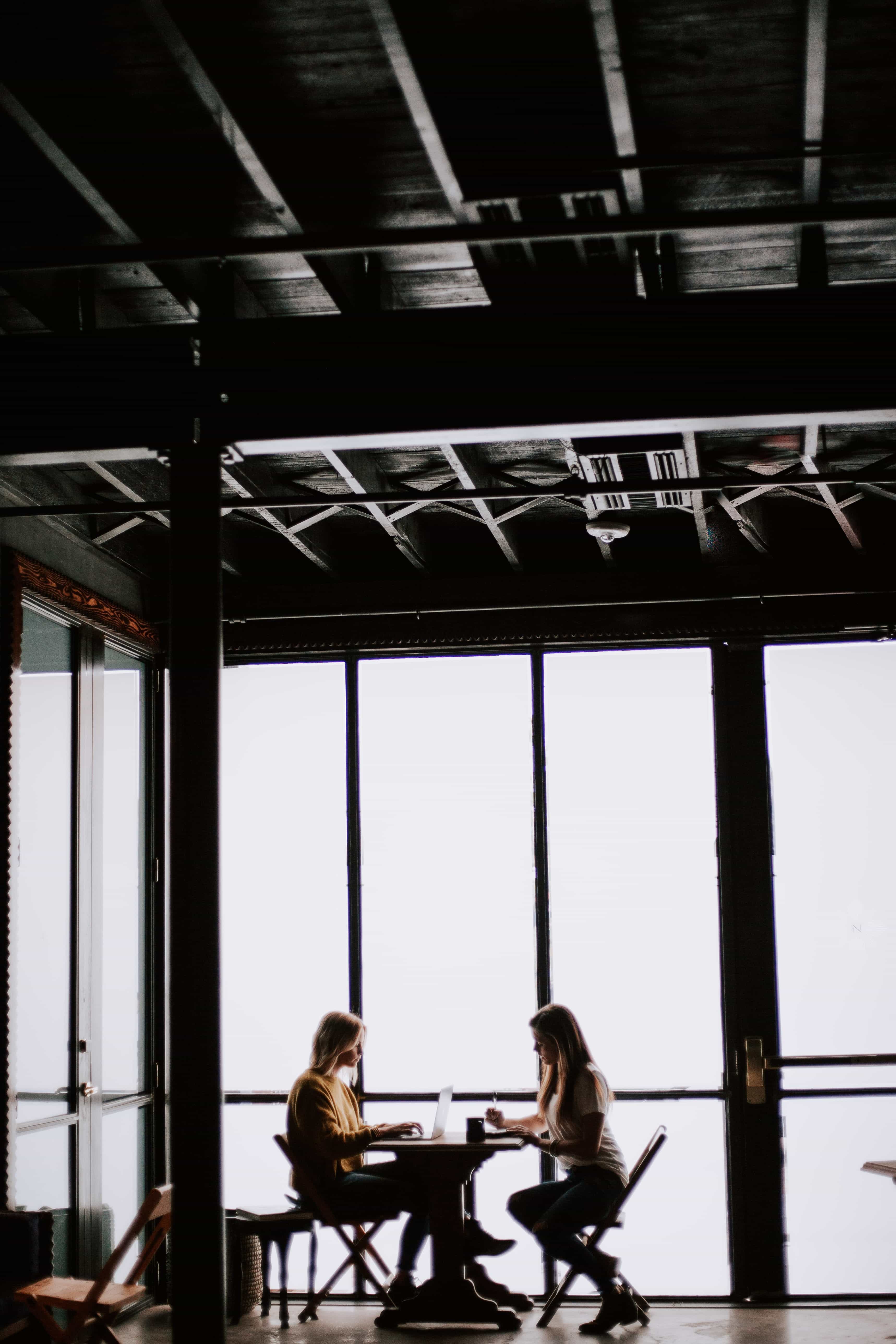 Two business people sitting at a table in an open plan office