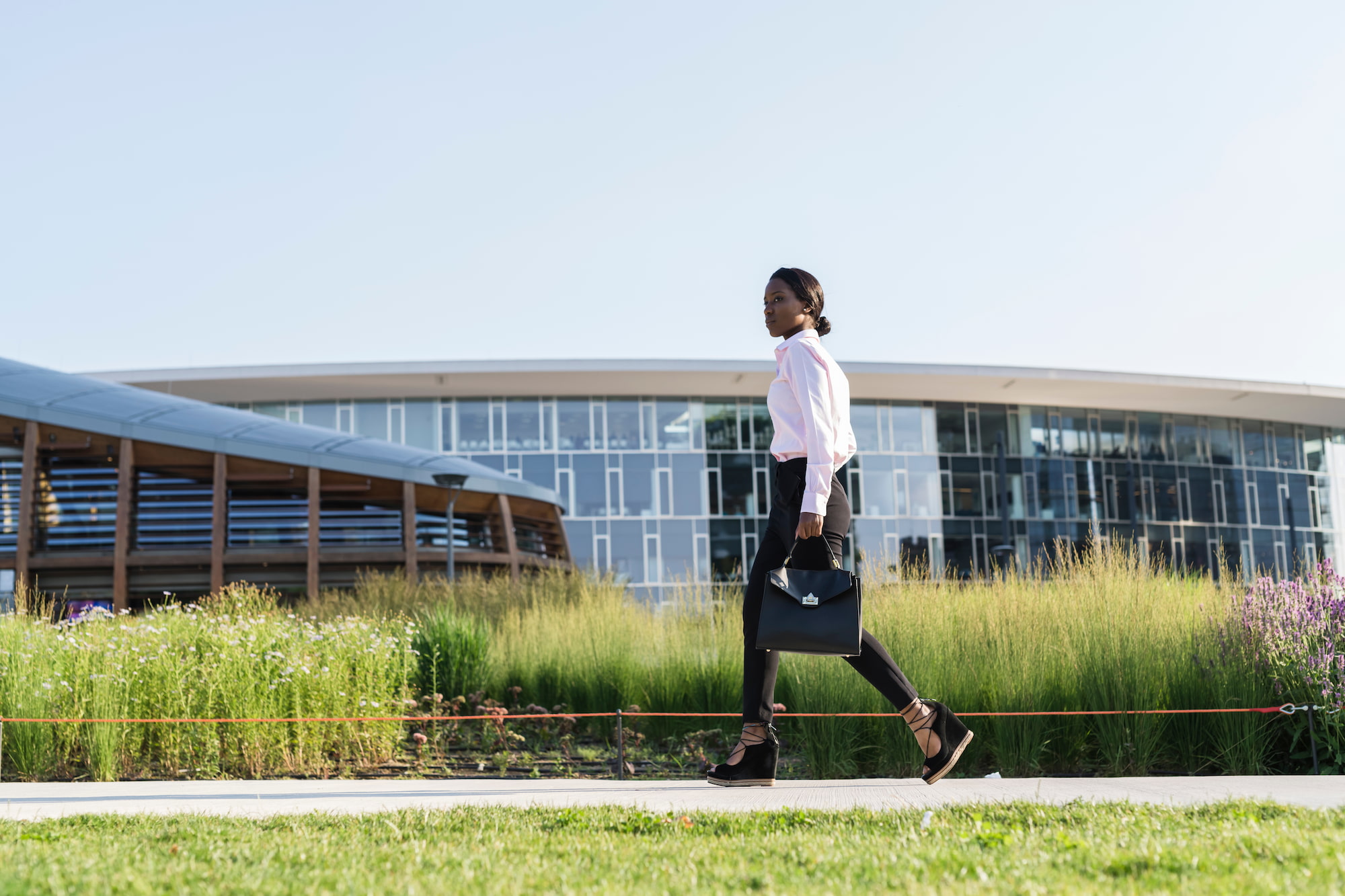 Image of a women holding a bag walking outside next to a building