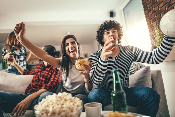 football fans watching from home while eating snacks