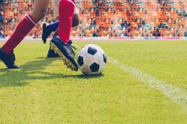 close up shot of a football athlete's feet kicking a football