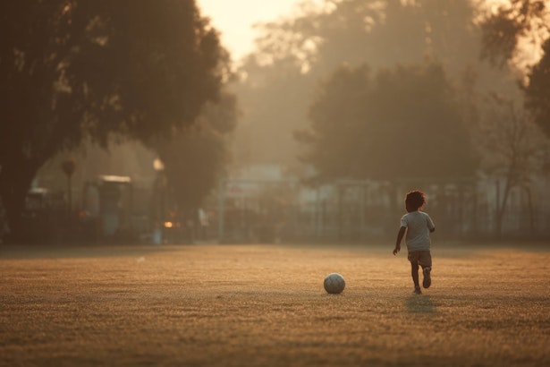 young boy running on a field with a soccer ball