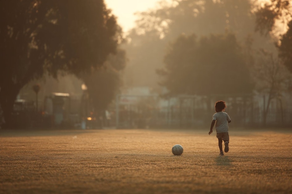 young boy running on a field with a soccer ball