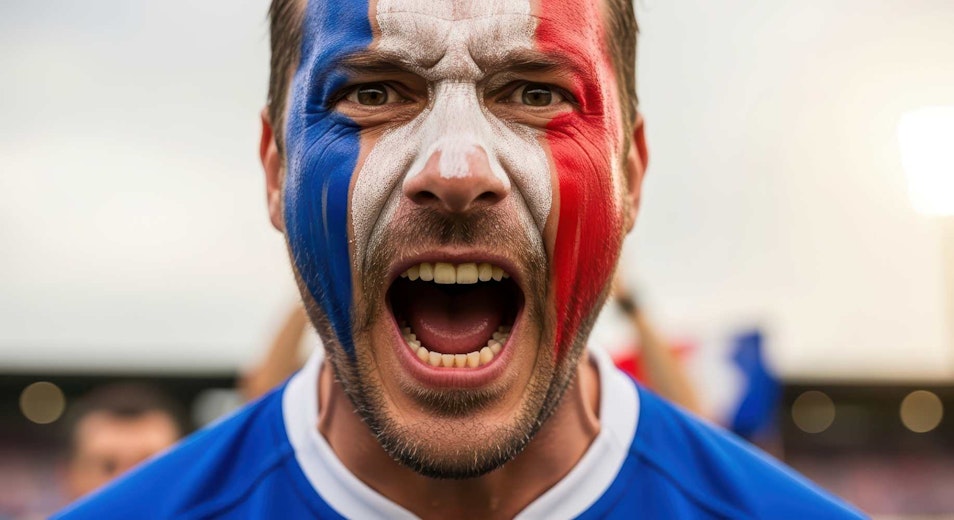 Caucasian male football fan with french flag face paint expressing excitement at stadium