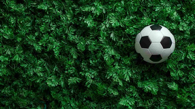 Soccer ball resting on bright simplicity artificial turf, embodying athletic green and sporting anticipation