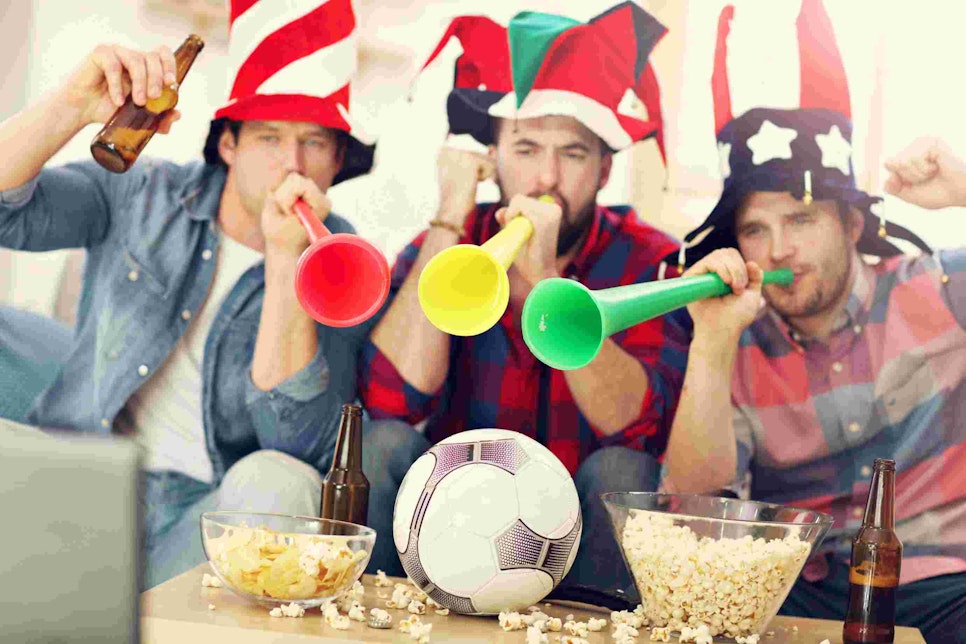 Happy male friends cheering and watching sports on tv