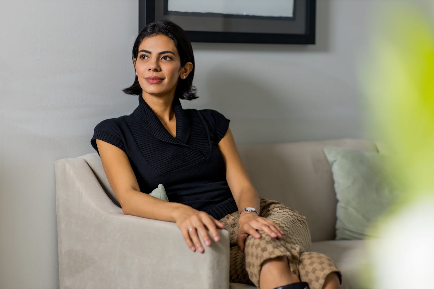 woman sitting on a couch in a black top and gucci pants