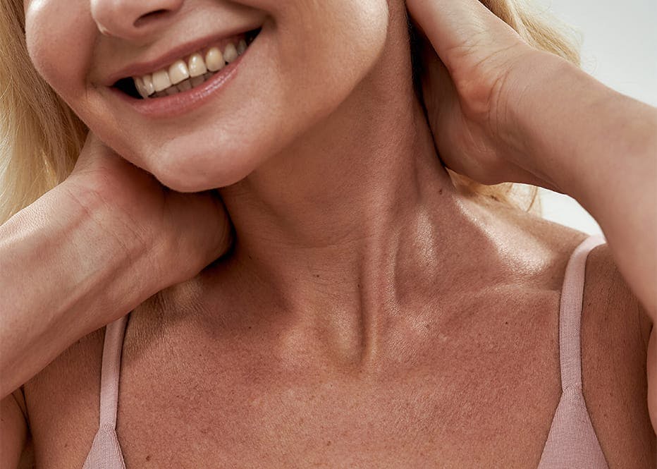 close up of woman's neck while she holds her hair back