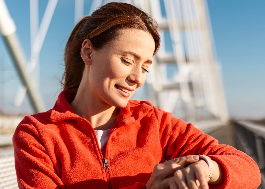 woman in red jacket looking at watch