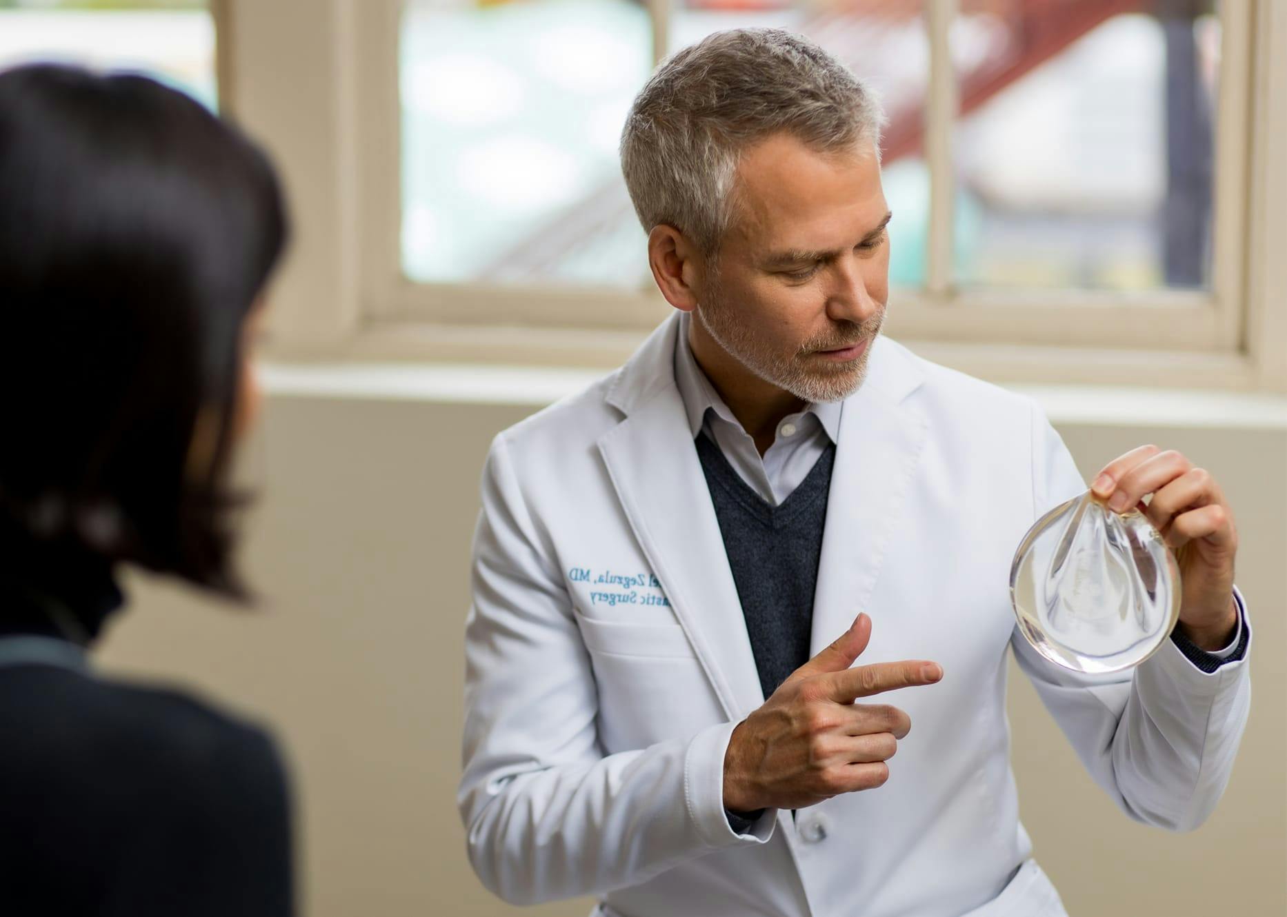 doctor pointing and showing client a breast implant