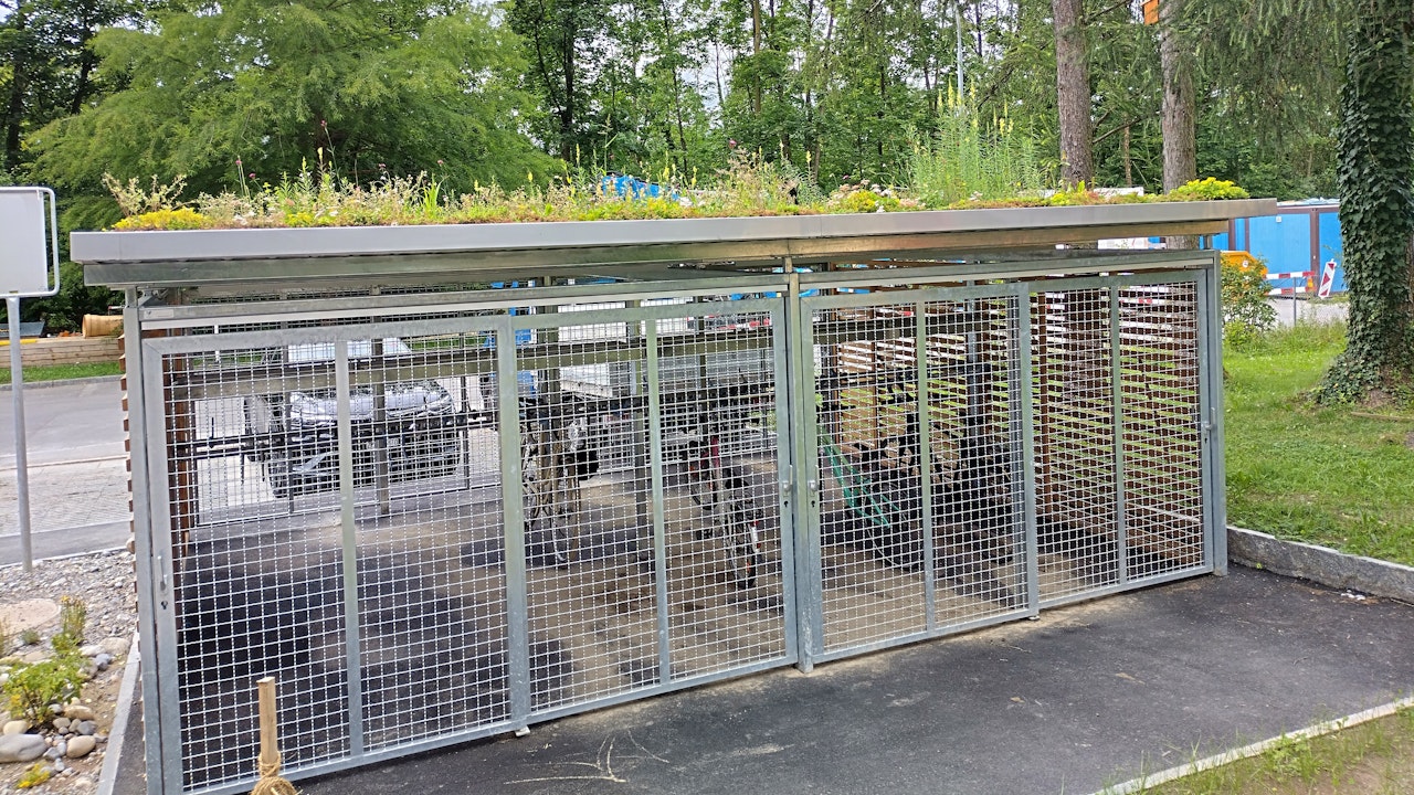 Das begrünte Dach eines Velounterstandes speichert Regenwasser, kühlt die Umgebung und bietet Lebensraum für Insekten.