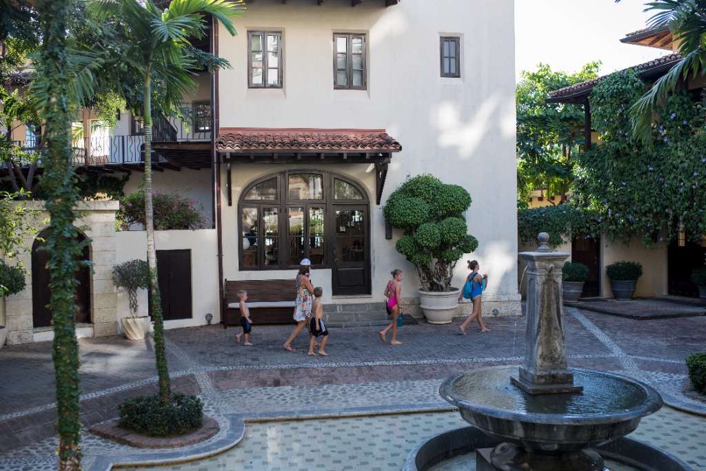 a family walking through cobblestone streets with a water fountain nearby