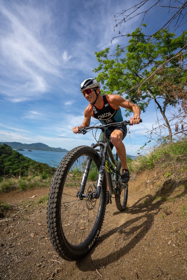 Man wearing a helmet on a bike on a trail near the ocean