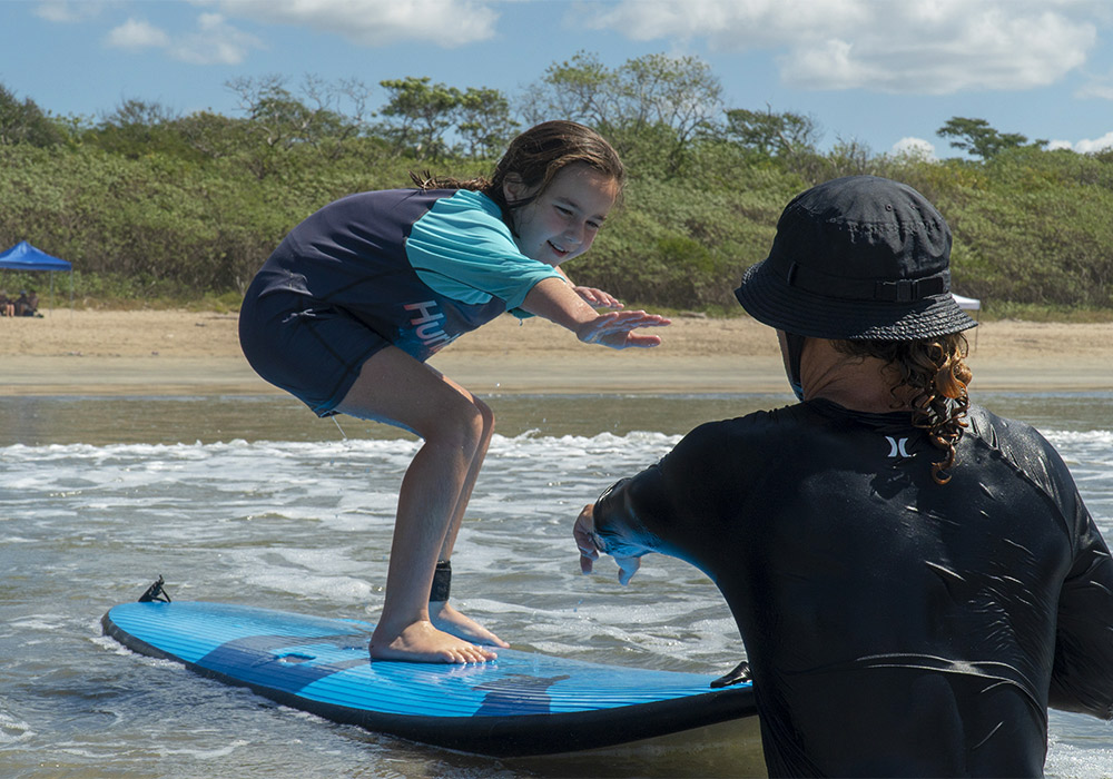 A child on a surf board in the water with an instructor