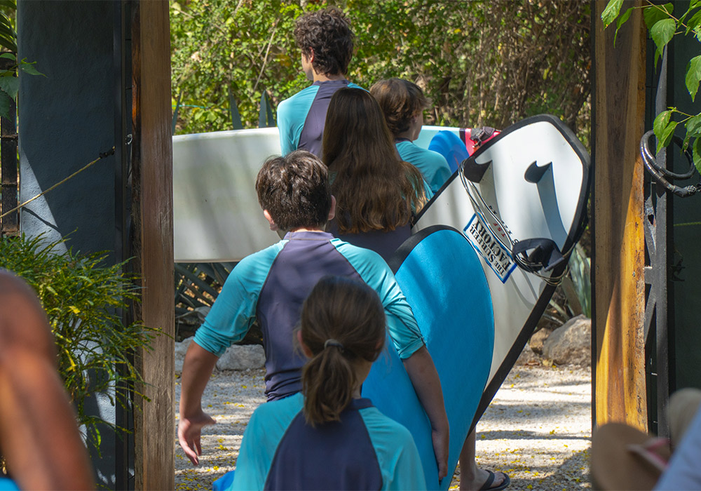 Five children holding surf boards walking