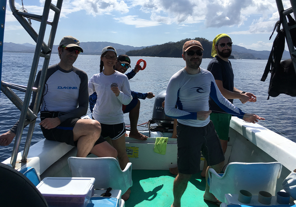 people on a boat in the ocean with an island in the distance