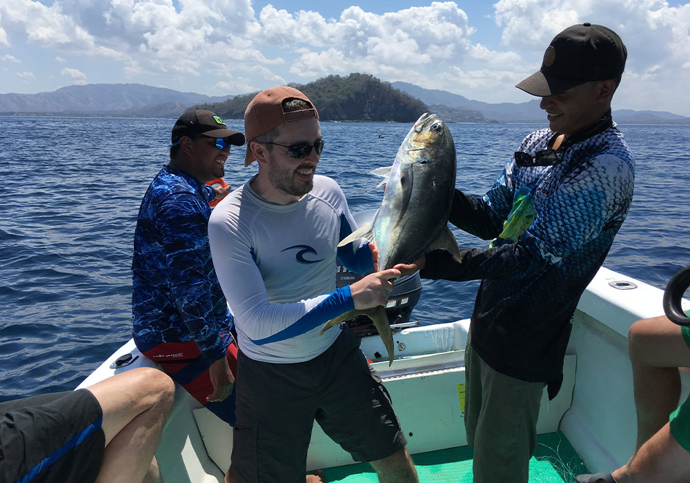 three people on a boat with a fish