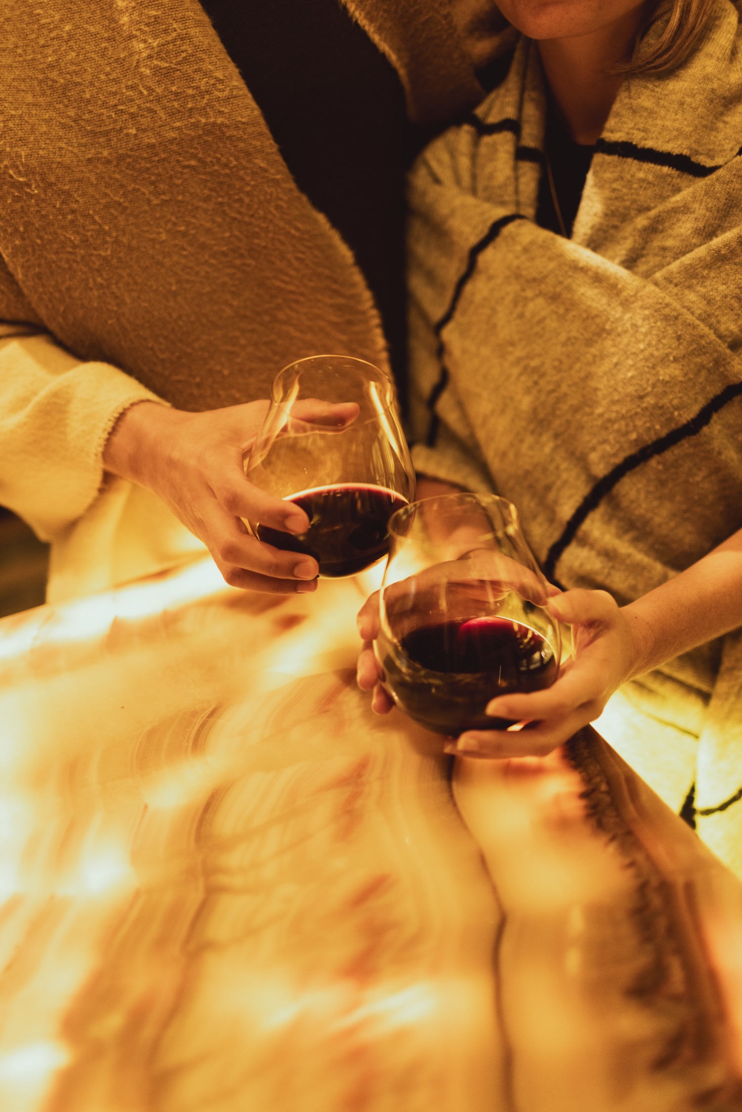 two hands holding glasses of red wine toasting