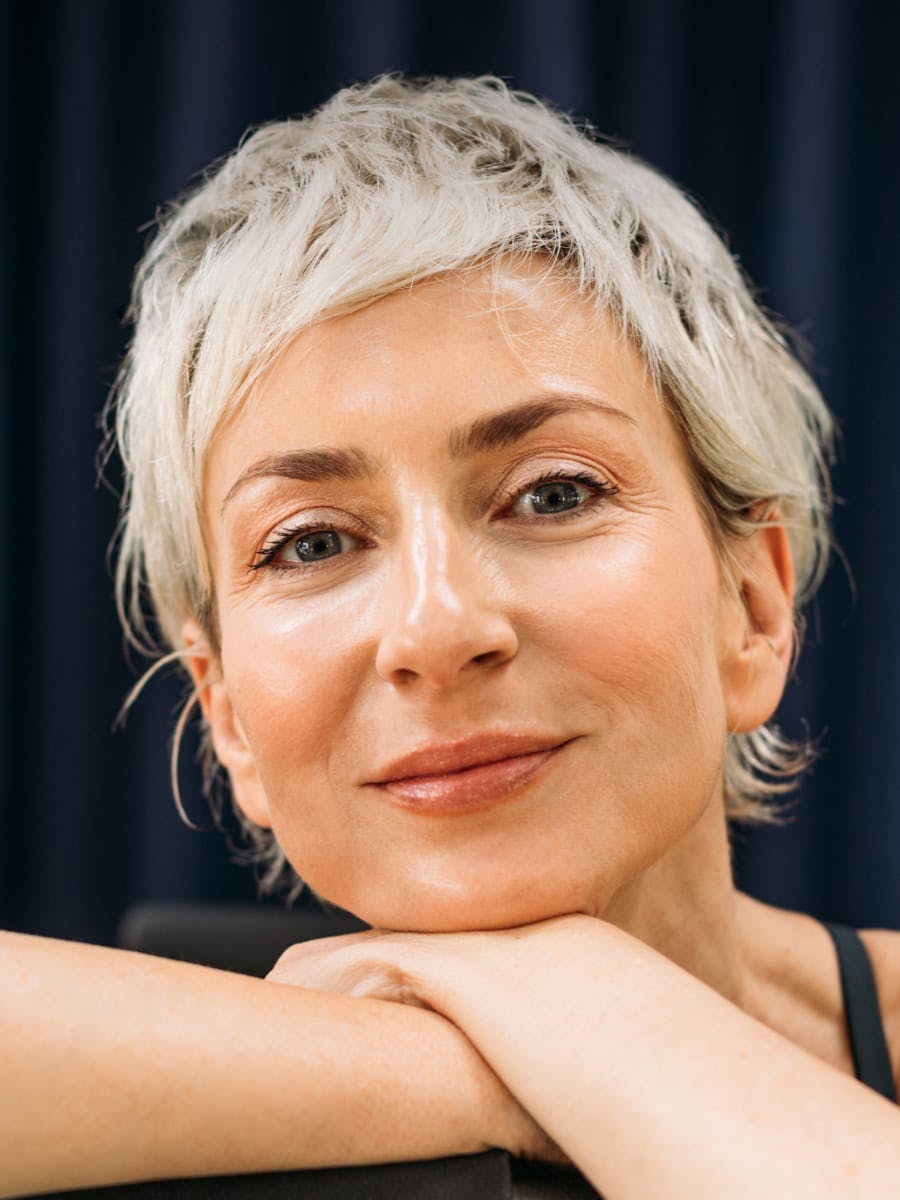 A woman with light blonde hair smiling resting on her hands
