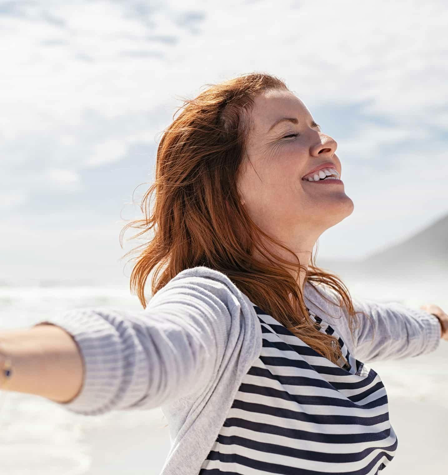 Woman outside smiling with arms out