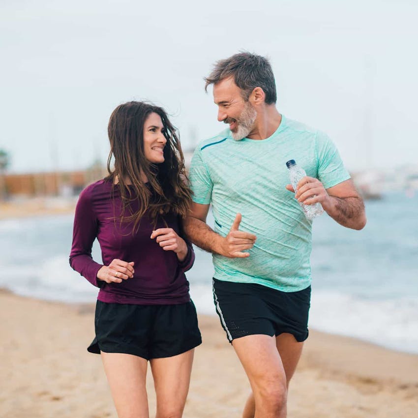 man and woman running on the beach