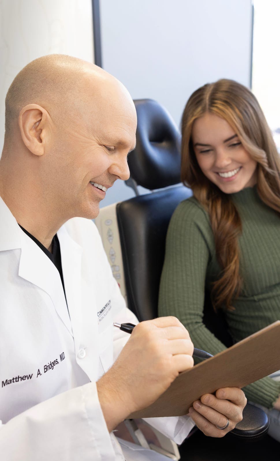Doctor Matthew Bridges pointing something out on a clipboard for a patient