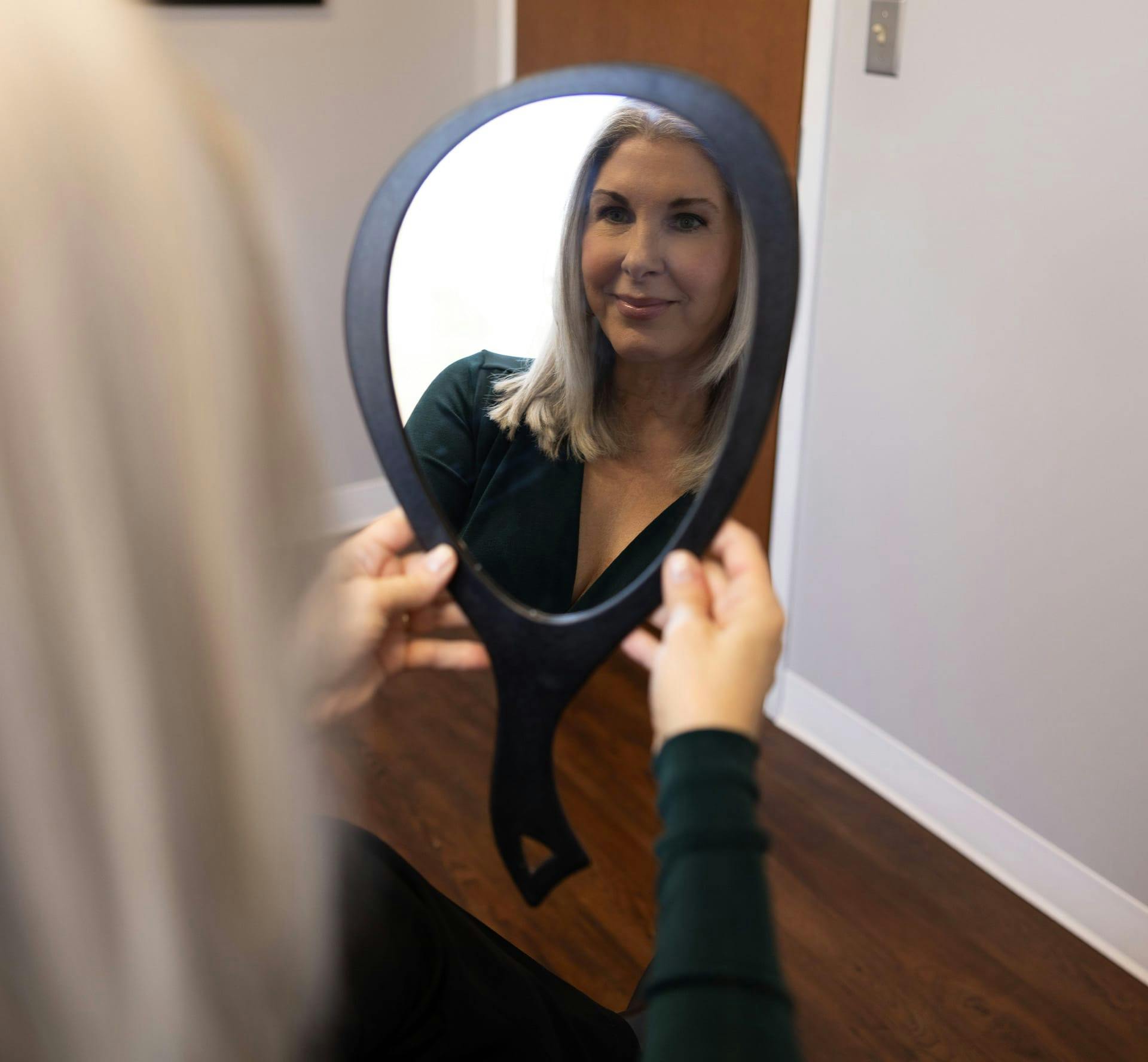 Woman looking in hand mirror