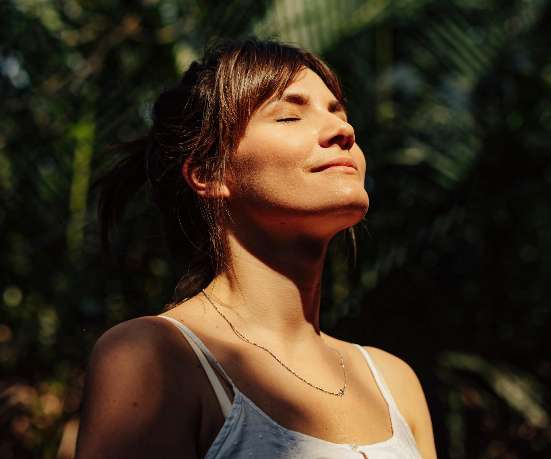 woman outside tilting her face up towards the sun