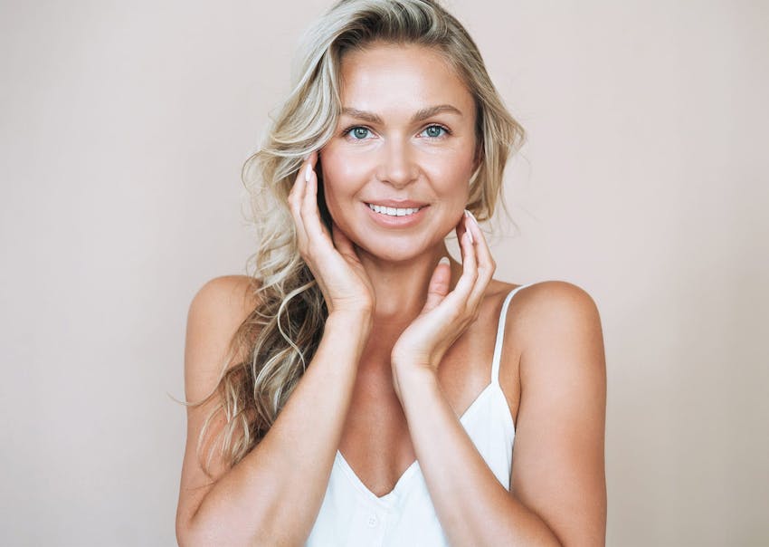 Woman in white top touching her cheeks