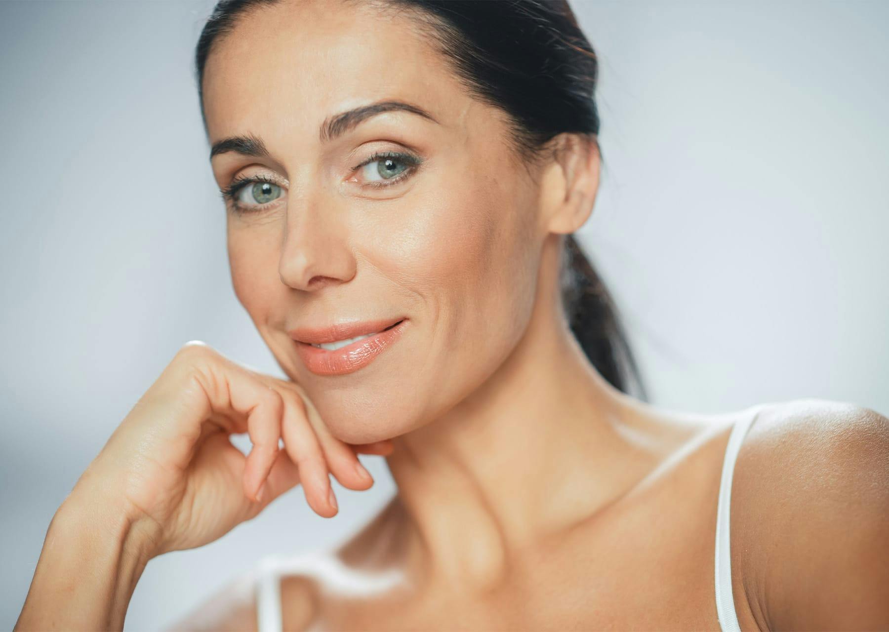 Woman smiling while resting chin on her hand
