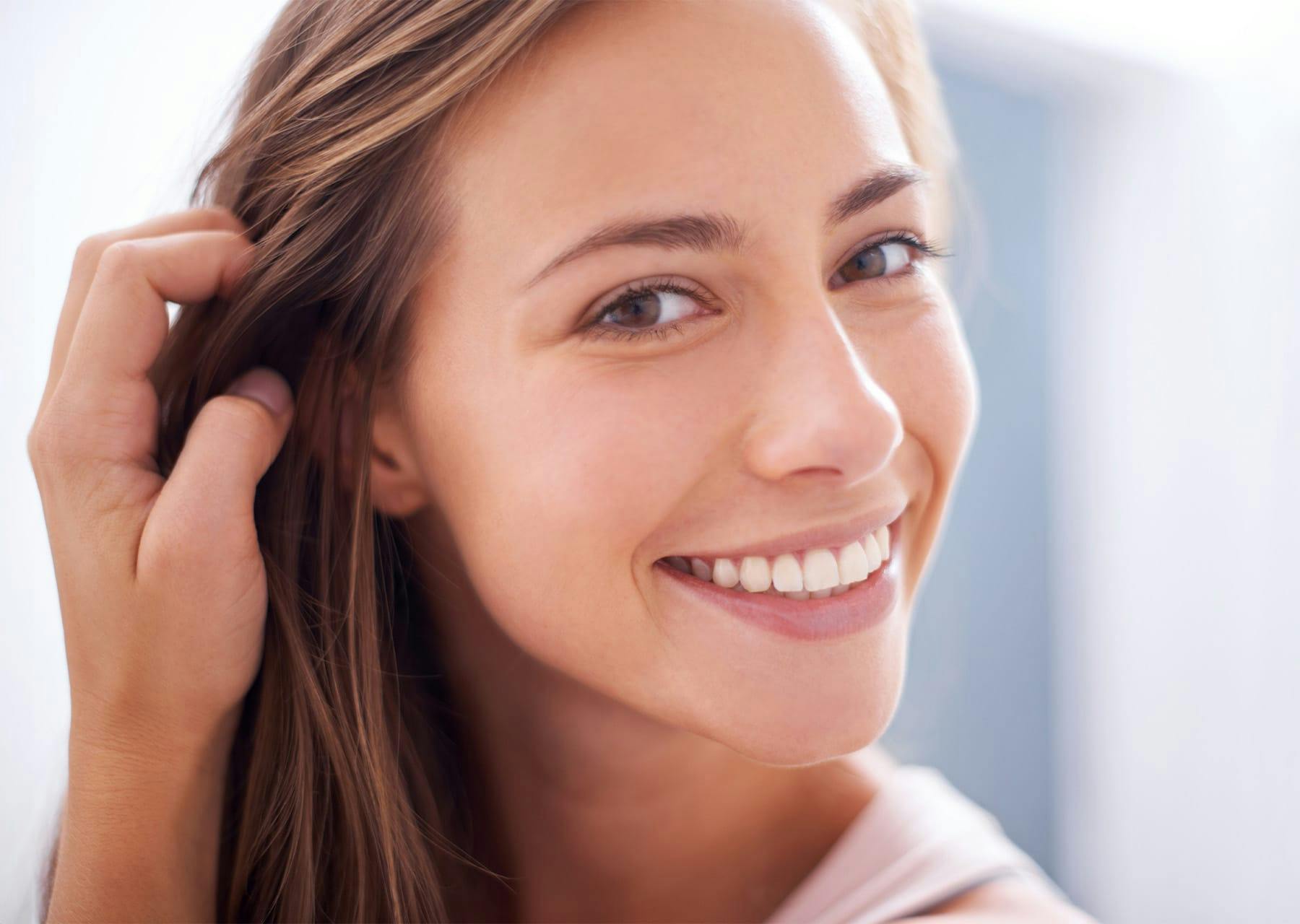Woman smiling while brushing back her hair