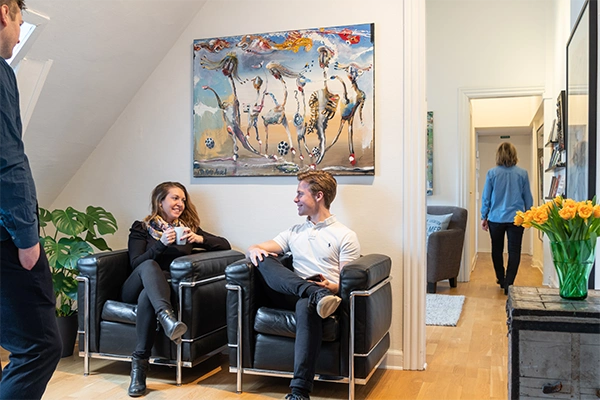 en kvinde og mand snakker sammen i hyggeligt lounge område hos Compass