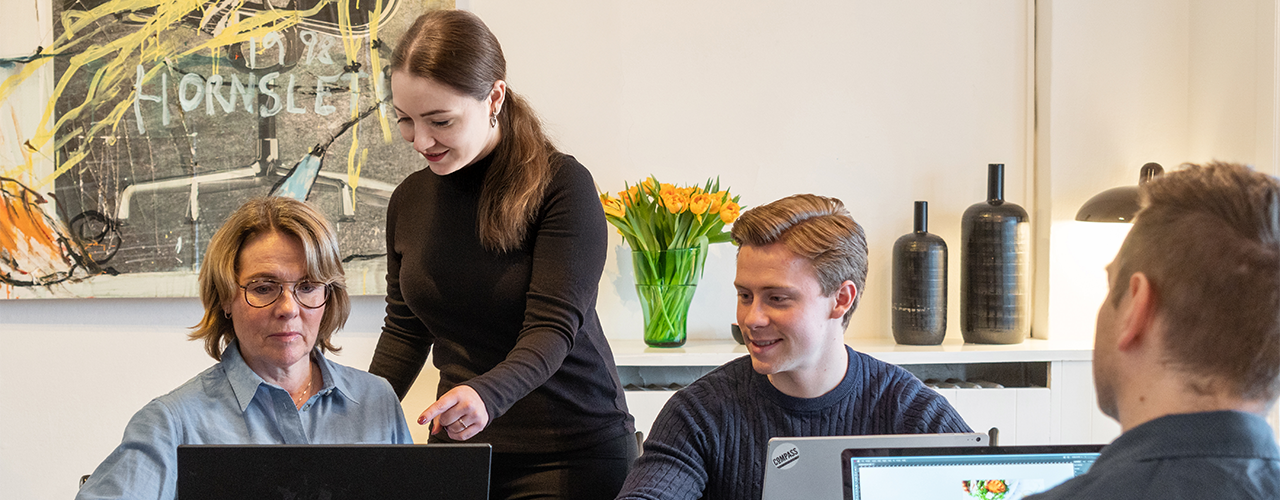 En kvindelig underviser hos Compass er ved at undervise kursister på deres computere