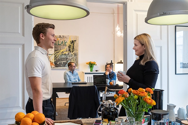 En kvinde og mand står og snakker ved kaffebordet hos Compass