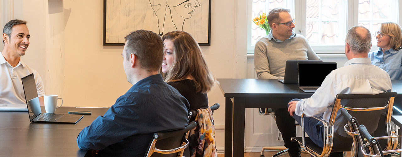 Kursister sidder og snakker sammen i kursuslokale hos Compass Academy