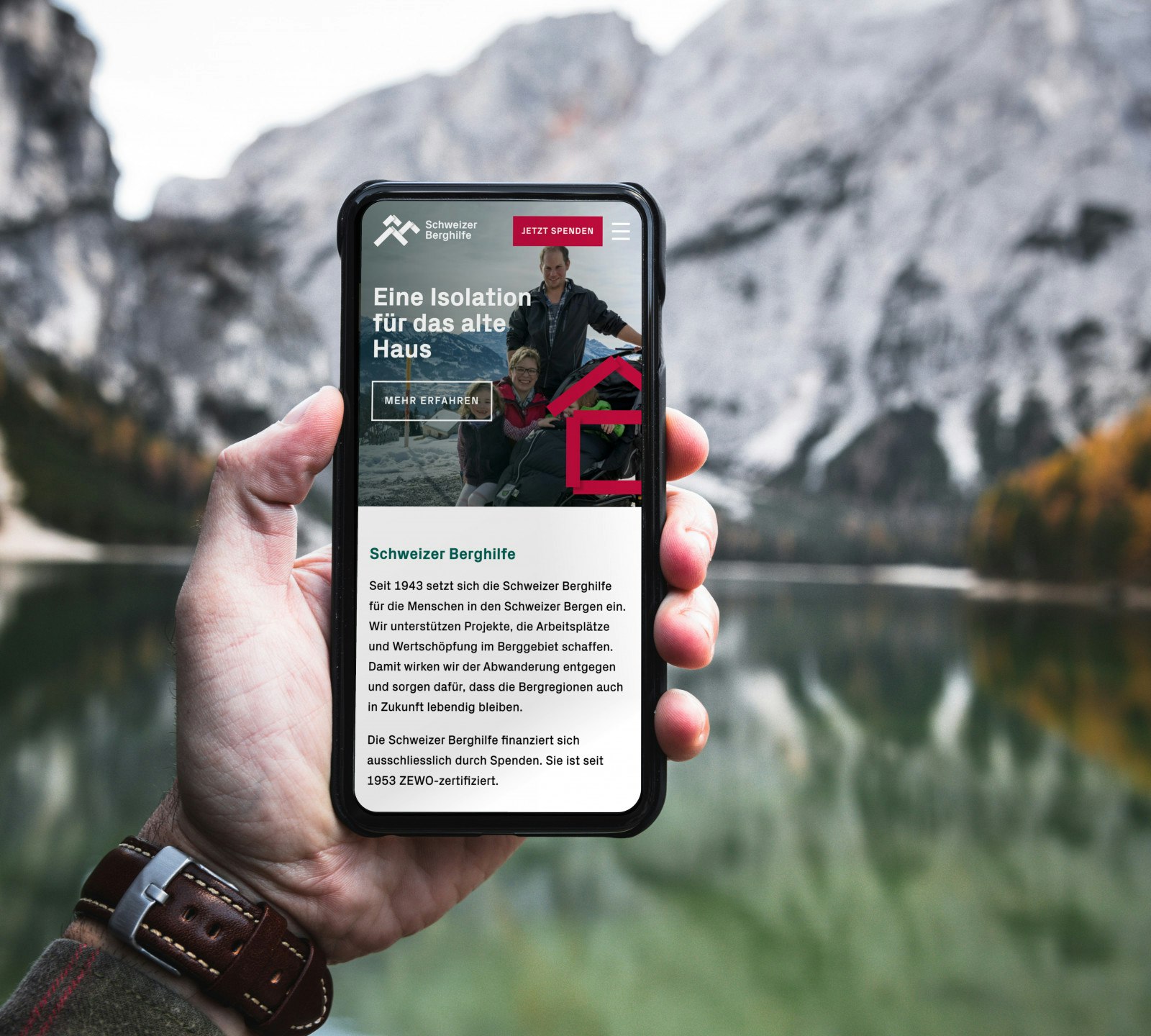 Person holding smartphone displaying a website with a mountainous background.