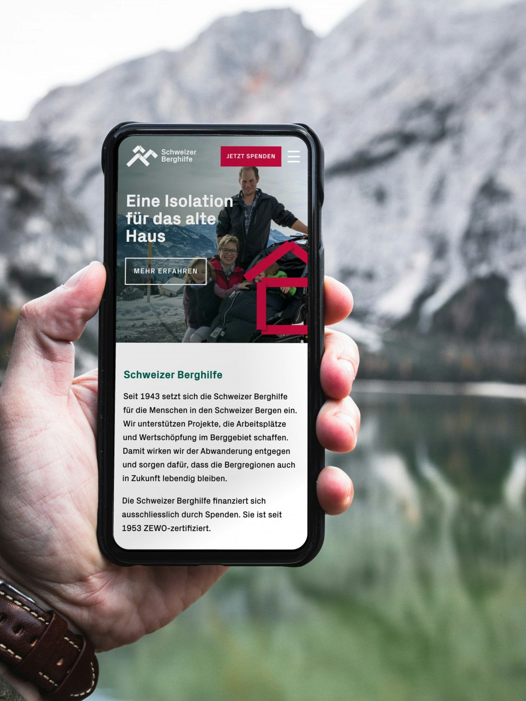 Person holding smartphone displaying a website with a mountainous background.