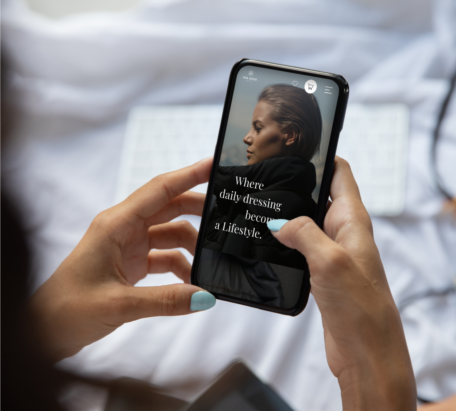 A person holding a smartphone with an on-screen fashion ad that reads, "Where daily dressing becomes a Lifestyle," in front of a blurred keyboard background.