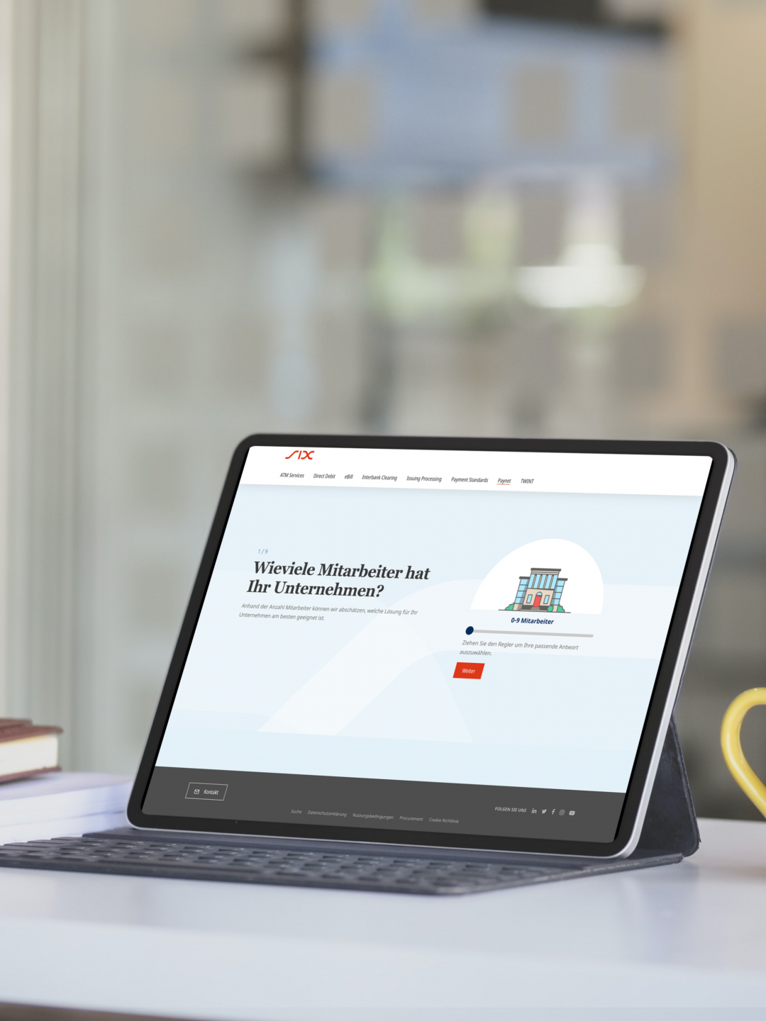 Tablet on a table displaying a website with a question about company employees. A keyboard case, a stack of books, and a yellow mug are also on the table.